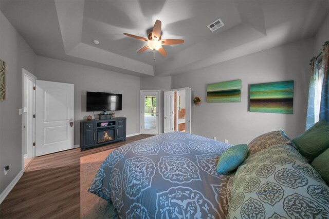 1840 Kamber Ter, Edmond, OK 73003 - bedroom with a tray ceiling, wood finished floors, ceiling fan, and a glass covered fireplace