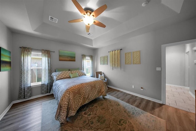 1840 Kamber Ter, Edmond, OK 73003 - bedroom with a raised ceiling, multiple windows, wood finished floors, and a ceiling fan
