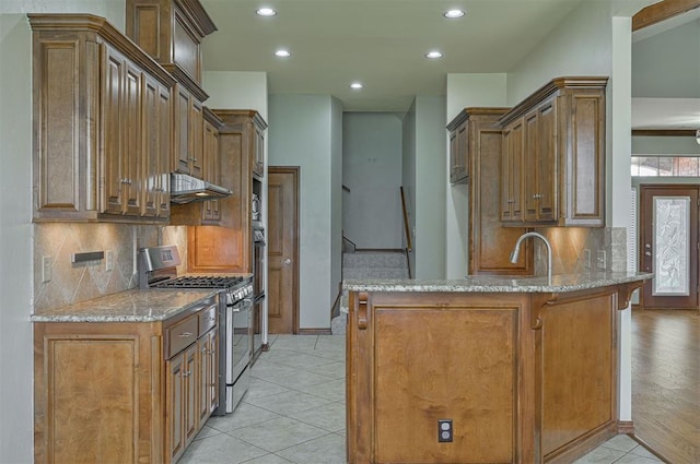 5404 NW 119th St, Oklahoma City, OK 73162 - kitchen featuring gas stove, a peninsula, light stone counters, recessed lighting, and decorative backsplash
