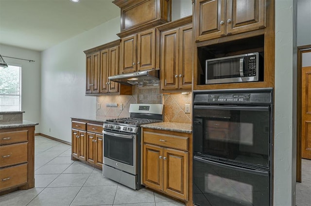 5404 NW 119th St, Oklahoma City, OK 73162 - kitchen featuring appliances with stainless steel finishes, under cabinet range hood, decorative backsplash, light tile patterned flooring, and light stone counters