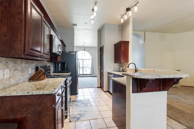 2001 Fair Meadow Dr, Edmond, OK 73003 - kitchen with appliances with stainless steel finishes, a peninsula, a kitchen bar, light tile patterned flooring, and arched walkways