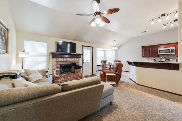 2001 Fair Meadow Dr, Edmond, OK 73003 - living room with a brick fireplace, a ceiling fan, vaulted ceiling, and light colored carpet