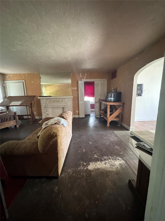 2701 NW 12th St, Oklahoma City, OK 73107 - living room featuring arched walkways, a textured ceiling, and concrete floors