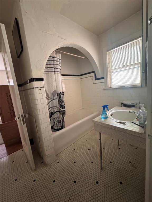 2701 NW 12th St, Oklahoma City, OK 73107 - full bath featuring tile patterned floors, vanity, tile walls, shower / bath combo with shower curtain, and wainscoting