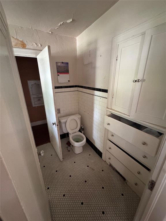 2701 NW 12th St, Oklahoma City, OK 73107 - bathroom featuring toilet and a wainscoted wall