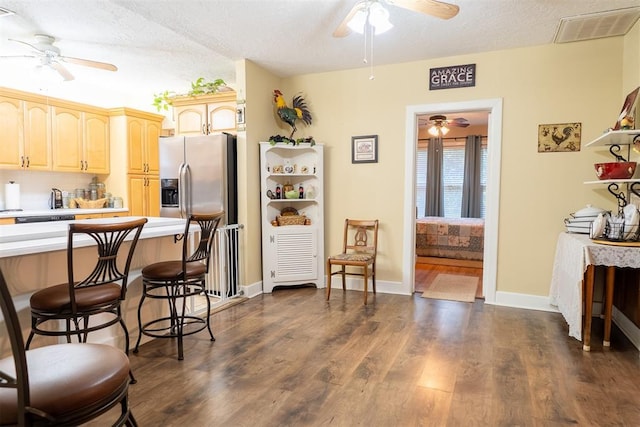 828 N Pine St, Pauls Valley, OK 73075 - kitchen with a ceiling fan, light countertops, a kitchen bar, light brown cabinetry, and dark wood-type flooring