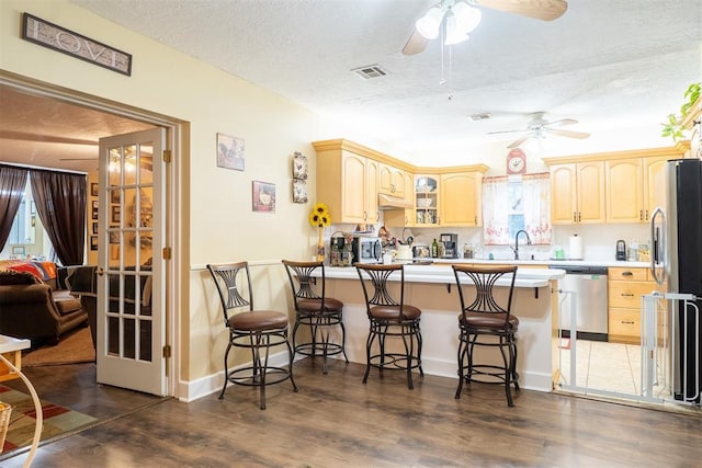 828 N Pine St, Pauls Valley, OK 73075 - kitchen with stainless steel appliances, a peninsula, a ceiling fan, wood finished floors, and glass insert cabinets