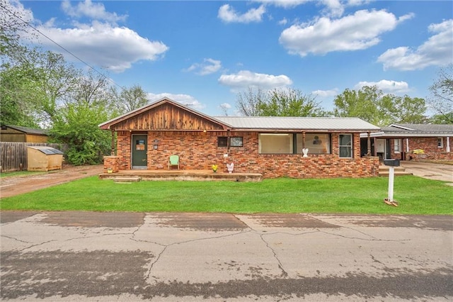 207 E Pine Ave, Sayre, OK 73662 - view of front of property with dirt driveway, a front yard, a metal roof, and brick siding