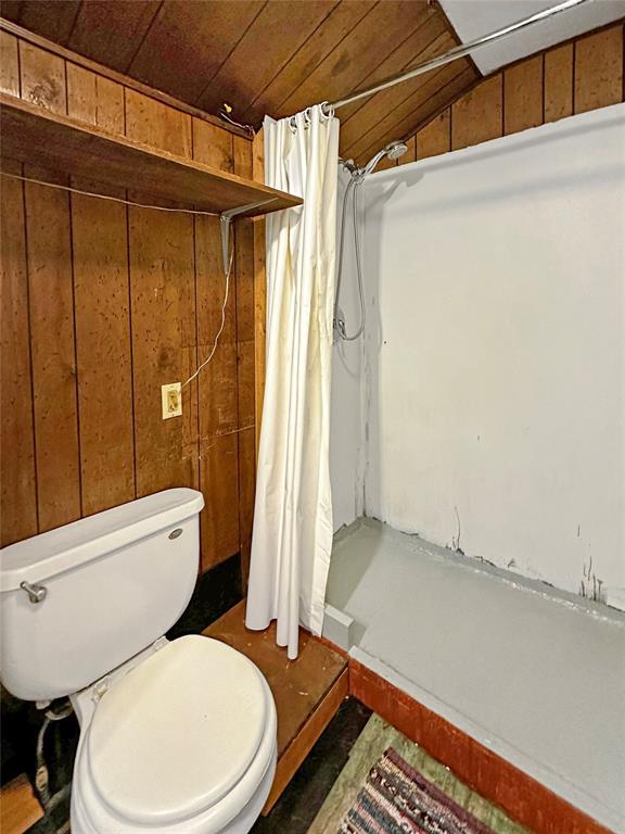 207 E Pine Ave, Sayre, OK 73662 - full bath featuring a stall shower, lofted ceiling, wooden ceiling, and wood walls