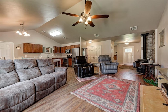 19100 SE 134th St, Mcloud, OK 74851 - living area with a wood stove, wood finished floors, a ceiling fan, lofted ceiling, and a chandelier