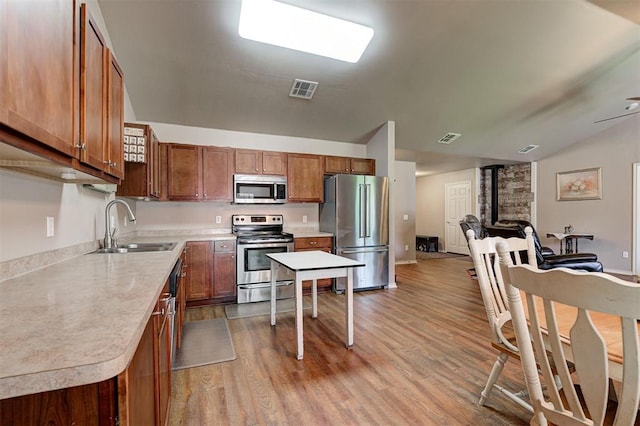 19100 SE 134th St, Mcloud, OK 74851 - kitchen with appliances with stainless steel finishes, wood finished floors, vaulted ceiling, and brown cabinetry