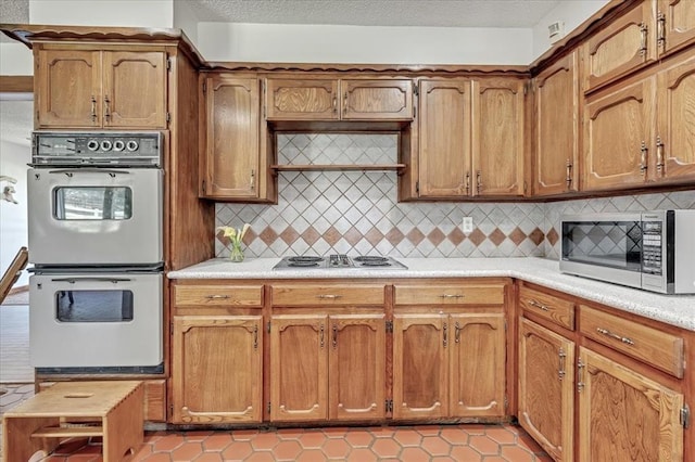 331249 E 1020th Rd, Harrah, OK 73045 - kitchen featuring multiple ovens, stainless steel microwave, white electric cooktop, light tile patterned floors, and light countertops