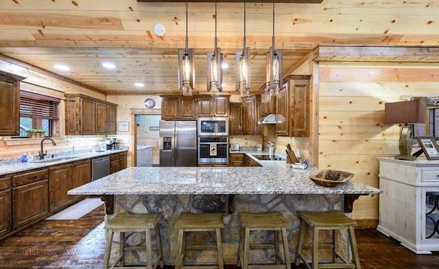 1723 Pine Hills Rd, Broken Bow, OK 74728 - kitchen featuring stainless steel appliances, light stone counters, a breakfast bar area, dark wood finished floors, and decorative light fixtures