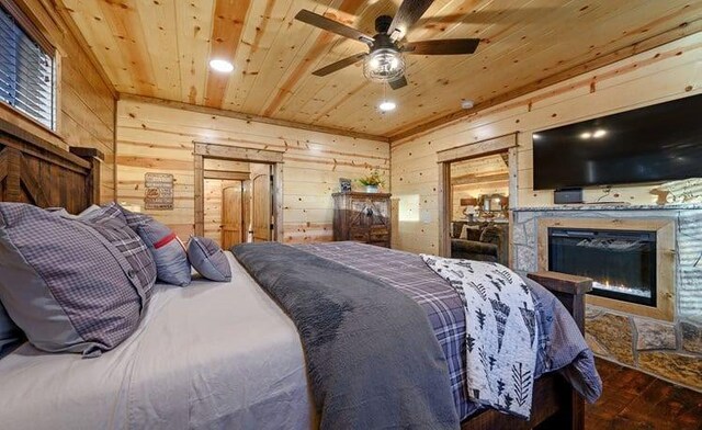 1723 Pine Hills Rd, Broken Bow, OK 74728 - bedroom with wood ceiling, wooden walls, a glass covered fireplace, wood finished floors, and recessed lighting