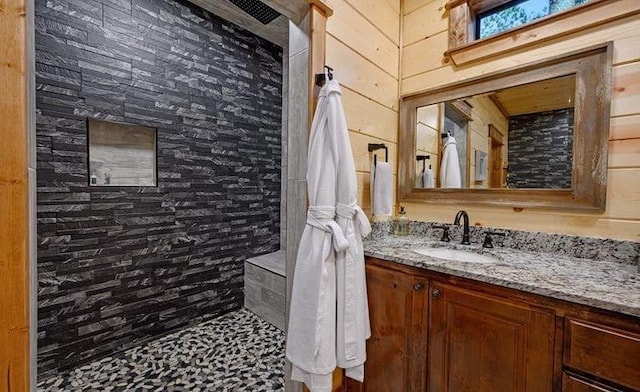 1723 Pine Hills Rd, Broken Bow, OK 74728 - bathroom featuring wood walls, a tile shower, and vanity