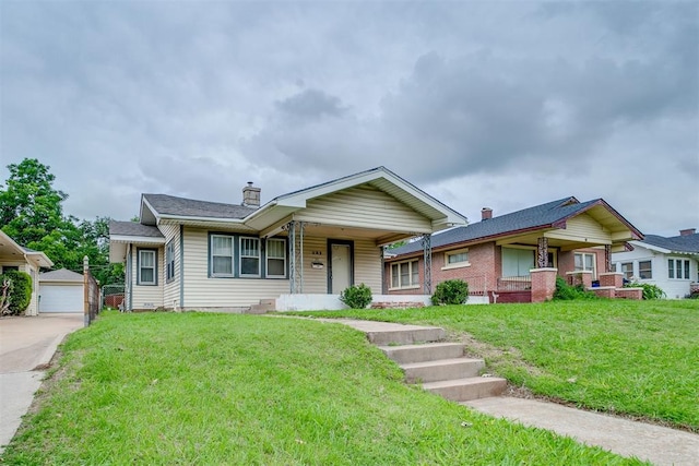 121 NW 26th St, Oklahoma City, OK 73103 - view of front of home featuring covered porch, a chimney, a front lawn, and an outbuilding