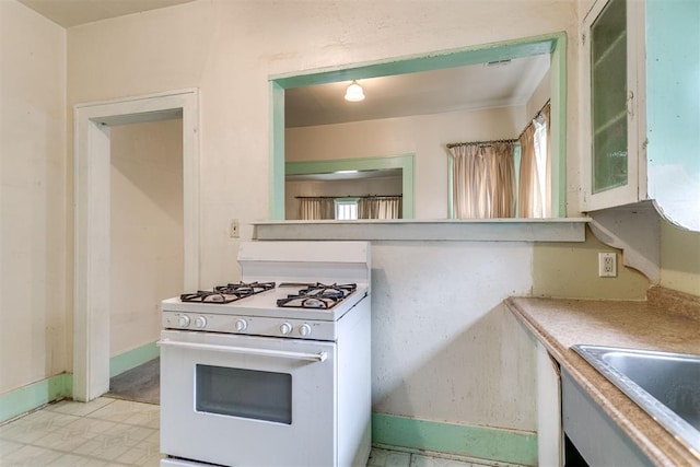 121 NW 26th St, Oklahoma City, OK 73103 - kitchen with white gas stove, glass insert cabinets, and light countertops