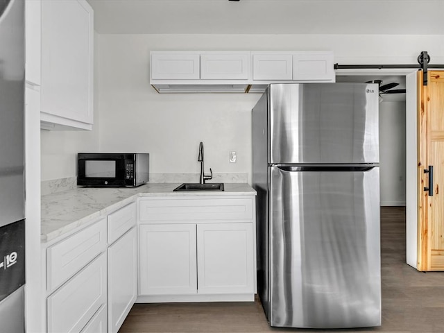 500 W Simpson Rd, Edmond, OK 73034 - kitchen with freestanding refrigerator, black microwave, white cabinets, and wood finished floors