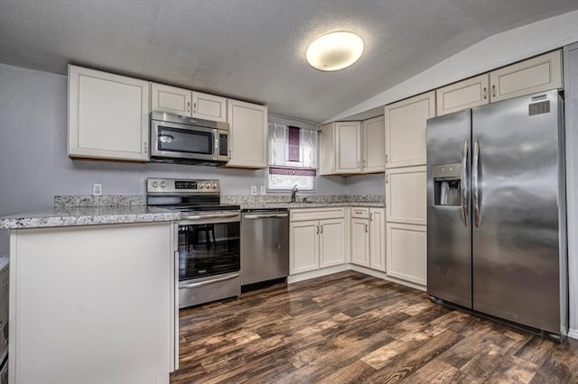 6550 N Indian Meridian Rd, Coyle, OK 73027 - kitchen featuring stainless steel appliances, vaulted ceiling, dark wood finished floors, light stone counters, and a textured ceiling