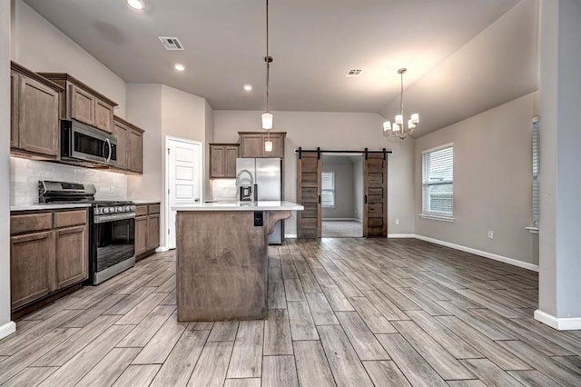 4217 NW 151st St, Edmond, OK 73013 - kitchen with stainless steel appliances, a barn door, light wood-style flooring, backsplash, and light countertops