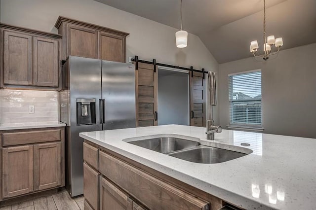 4217 NW 151st St, Edmond, OK 73013 - kitchen featuring stainless steel refrigerator with ice dispenser, a barn door, lofted ceiling, light stone counters, and pendant lighting