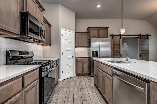 4217 NW 151st St, Edmond, OK 73013 - kitchen with appliances with stainless steel finishes, a barn door, backsplash, pendant lighting, and vaulted ceiling