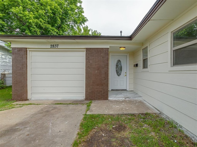 2837 SW 63rd St, Oklahoma City, OK 73159 - view of exterior entry featuring driveway, brick siding, and an attached garage