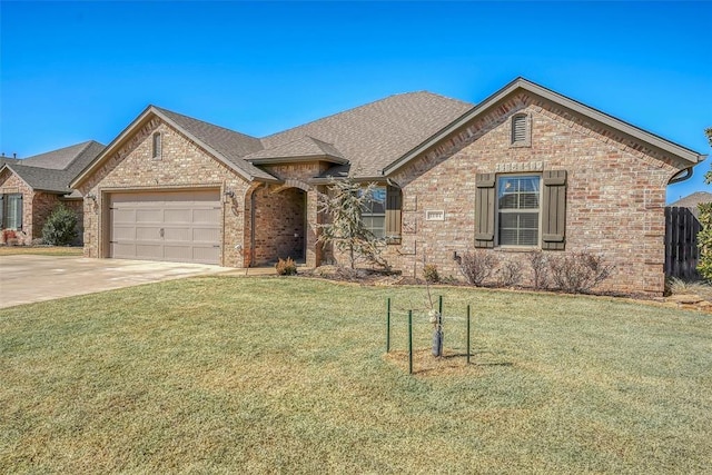 1101 Northridge Blvd, Altus, OK 73521 - french country home featuring brick siding, concrete driveway, a garage, a front yard, and roof with shingles