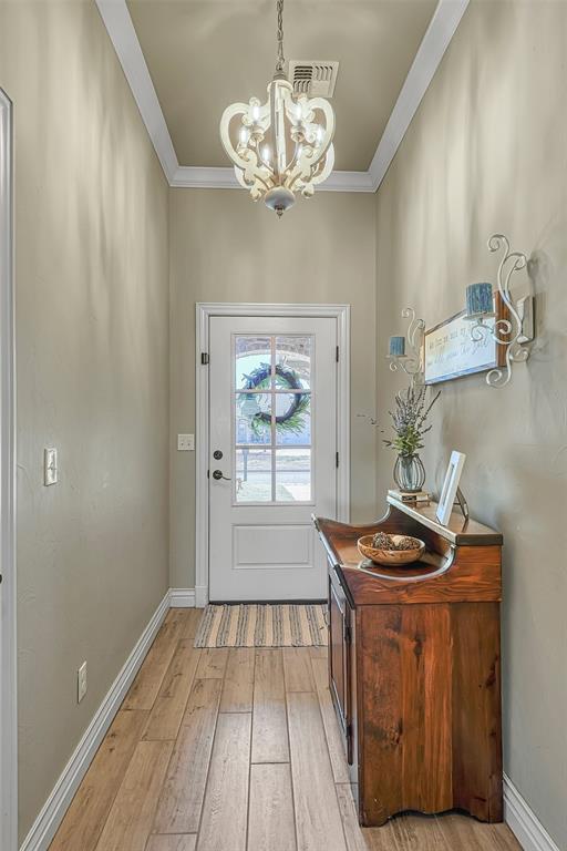 1101 Northridge Blvd, Altus, OK 73521 - entryway with a chandelier, light wood-style floors, and ornamental molding