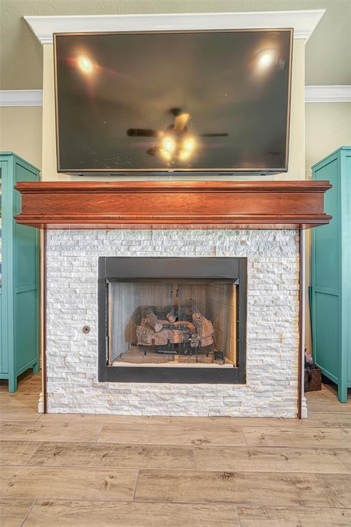 1101 Northridge Blvd, Altus, OK 73521 - detailed view of a stone fireplace, crown molding, wood finished floors, and ceiling fan