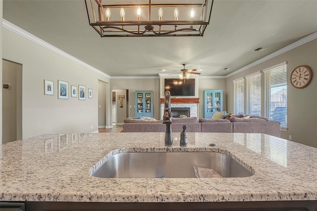 1101 Northridge Blvd, Altus, OK 73521 - kitchen featuring open floor plan, light stone counters, crown molding, a fireplace, and ceiling fan