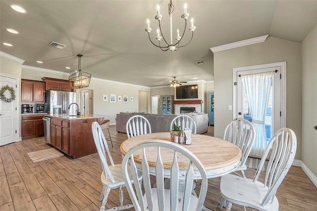 1101 Northridge Blvd, Altus, OK 73521 - dining room with a fireplace, a chandelier, crown molding, light wood-style flooring, and recessed lighting