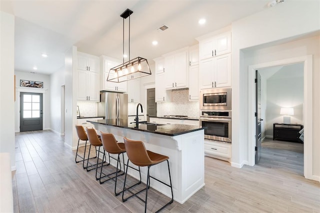 16101 Villa Valeria Way, Edmond, OK 73013 - kitchen featuring appliances with stainless steel finishes, dark countertops, tasteful backsplash, light wood finished floors, and a breakfast bar area