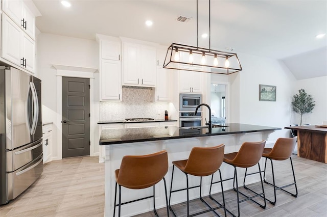 16101 Villa Valeria Way, Edmond, OK 73013 - kitchen with appliances with stainless steel finishes, tasteful backsplash, white cabinetry, a kitchen bar, and recessed lighting