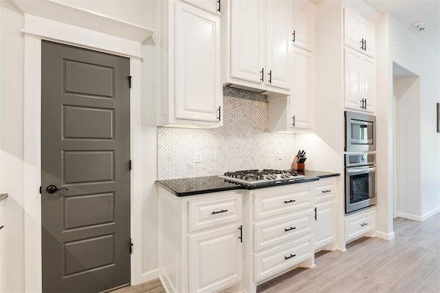 16101 Villa Valeria Way, Edmond, OK 73013 - kitchen with stainless steel appliances, dark countertops, backsplash, light wood-style floors, and white cabinets