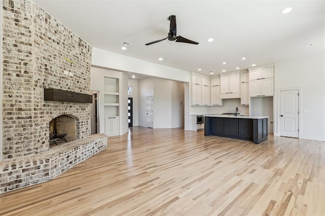 1690 Shaylee Ln, Choctaw, OK 73020 - kitchen with open floor plan, white cabinetry, light countertops, ceiling fan, and light wood finished floors