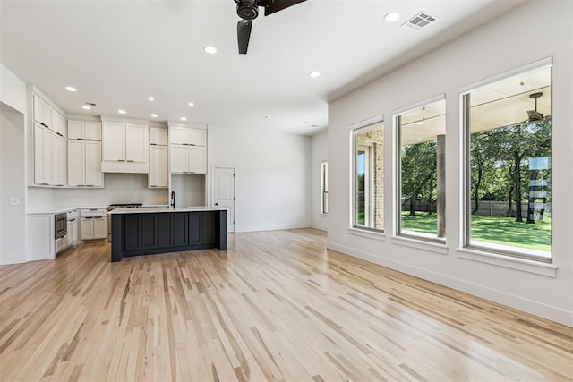 1690 Shaylee Ln, Choctaw, OK 73020 - kitchen with open floor plan, light wood finished floors, ceiling fan, recessed lighting, and a center island with sink