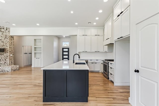 1690 Shaylee Ln, Choctaw, OK 73020 - kitchen with high end stainless steel range oven, light wood-type flooring, a center island with sink, white cabinetry, and light countertops