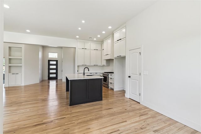 1690 Shaylee Ln, Choctaw, OK 73020 - kitchen featuring stainless steel range oven, white cabinetry, a kitchen island with sink, light wood-style floors, and built in features