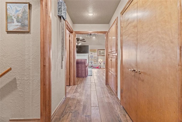 901 Gartrell Pl, Weatherford, OK 73096 - hall featuring a textured wall, wood-type flooring, and a textured ceiling