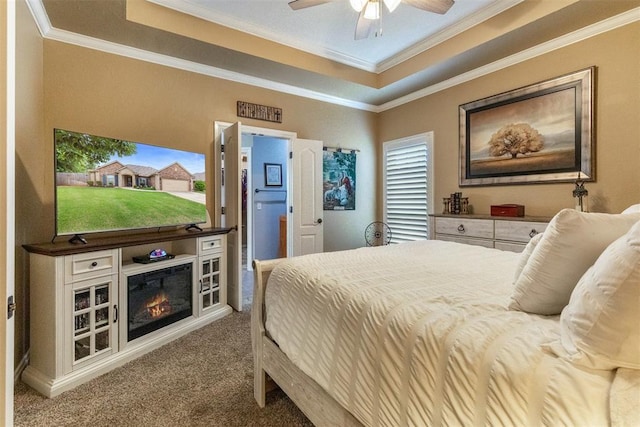 1106 Prairie Dunes Ct, Norman, OK 73072 - carpeted bedroom with crown molding, a tray ceiling, a ceiling fan, and a glass covered fireplace