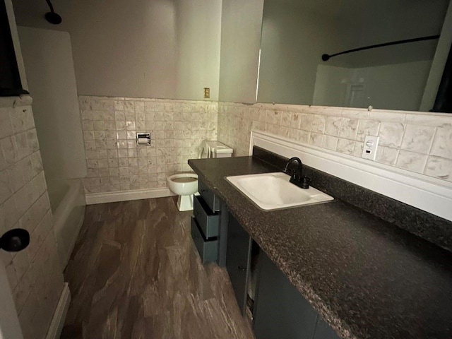 115 S Main St, Sharon, OK 73857 - full bath with tile walls, wood finished floors, vanity, a tub to relax in, and wainscoting