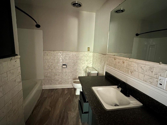 115 S Main St, Sharon, OK 73857 - bathroom with vanity, wood finished floors, a wainscoted wall, tile walls, and shower / bath combination
