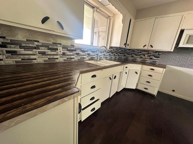 115 S Main St, Sharon, OK 73857 - kitchen featuring dark countertops, white microwave, decorative backsplash, and white cabinets