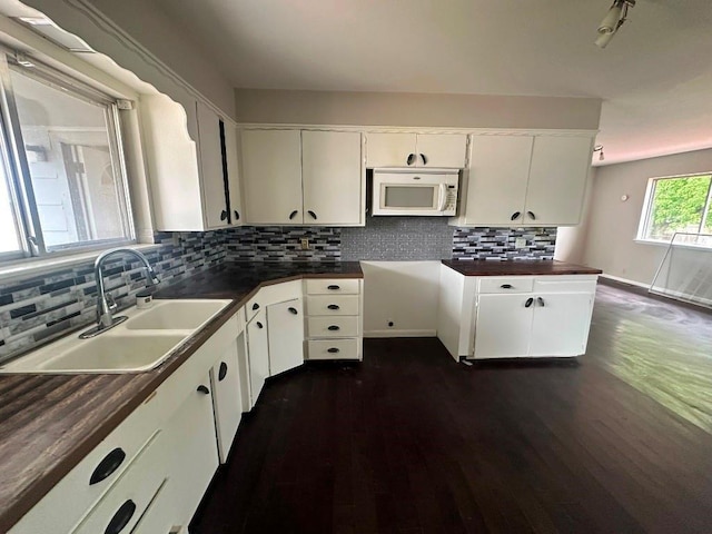 115 S Main St, Sharon, OK 73857 - kitchen featuring white microwave, dark countertops, dark wood-type flooring, and decorative backsplash