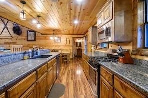 708 Split Creek Ln, Broken Bow, OK 74728 - kitchen with stainless steel appliances, wood finished floors, wood ceiling, brown cabinetry, and dark countertops