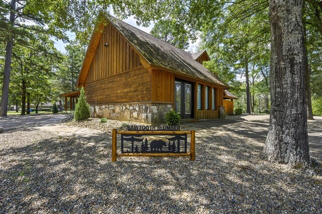 99 Sawtooth Pine Rd, Broken Bow, OK 74728 - view of home's exterior with french doors, stone siding, roof with shingles, and board and batten siding
