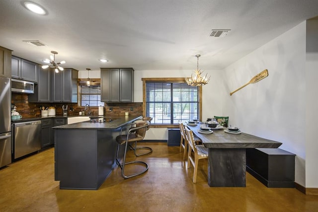 99 Sawtooth Pine Rd, Broken Bow, OK 74728 - kitchen with a chandelier, appliances with stainless steel finishes, dark countertops, tasteful backsplash, and finished concrete flooring