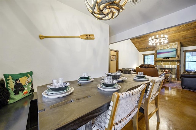 99 Sawtooth Pine Rd, Broken Bow, OK 74728 - dining area with a chandelier, lofted ceiling, concrete floors, and a fireplace