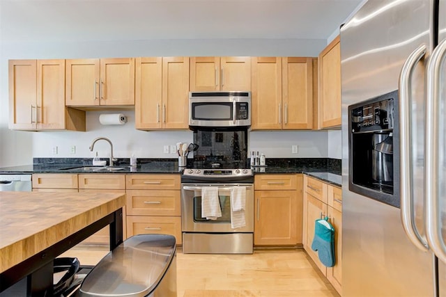 444 N Central Ave Unit 106, Oklahoma City, OK 73104 - kitchen featuring stainless steel appliances, light brown cabinets, light wood finished floors, and dark stone countertops